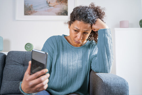 Sad black woman reading bad news on smart phone