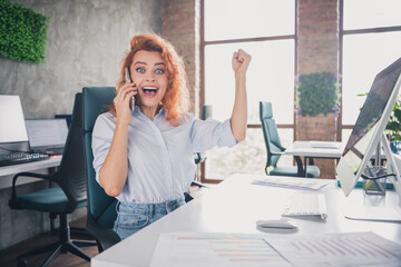 Obraz premium Portrait of young corporate worker lady raise fist communicate phone modern loft interior business center indoors