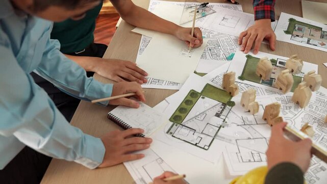 Architect and safety engineer discussion about building construction use blueprint on table with architectural document, measurement tool and wooden block scatter around at modern office. Delineation.