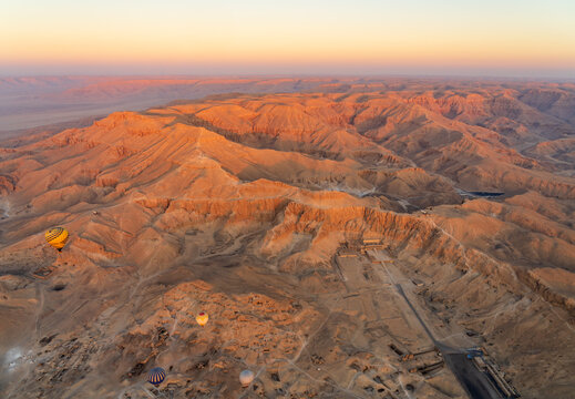 Aerial view of Hatshepsut Temple in Egypt at sunrise, showing the temple's architecture and surrounding desert landscape from hot air ballloon