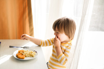 Toddler enjoying mealtime with a fork in a warm, sunny space, genuine and heartfelt moments.