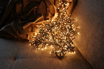 Warm christmas lights illuminating cozy sofa with blanket