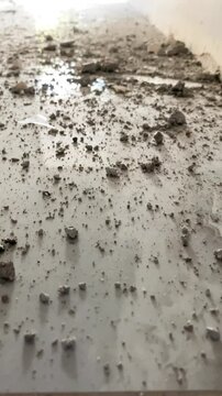 A close-up of debris scattered across the floor of a construction site in an unfinished apartment.
