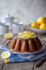 Torta di limone decorata con fette di limone su un tavolo di legno e dei panni di colore azzurro e blu
