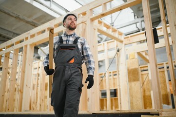 Fototapeta premium Modern modular house. A worker works on the construction of a wooden house