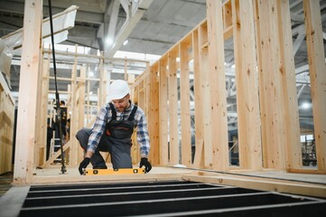 Fototapeta premium Construction of modular houses. A carpenter or builder builds a wooden house