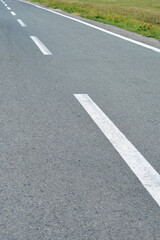 An asphalt road with dashed white lines marking traffic lanes