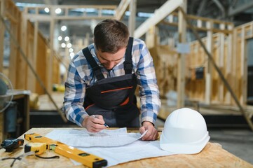 Modern modular houses. Architect wooden buildings. Man stands under frame wooden house. Man...
