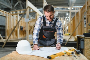 Modern modular houses. Architect wooden buildings. Man stands under frame wooden house. Man...