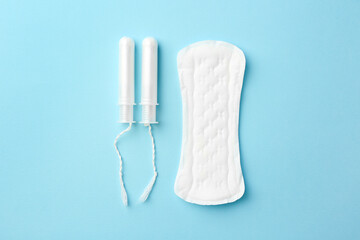 Menstrual pad and tampons on light blue background, top view