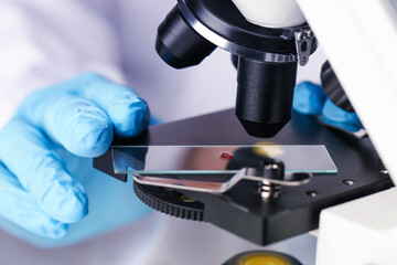 Scientist examining sample on slide under microscope, closeup