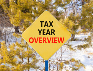 Tax year overview symbol. Concept words Tax year overview on beautiful yellow road sign. Beautiful snow forest background. Business tax year overview concept. Copy space.