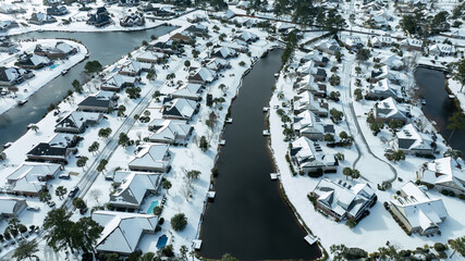 Aerial views of a snow-covered suburban neighborhood with houses, roads, ponds, and recreational facilities.