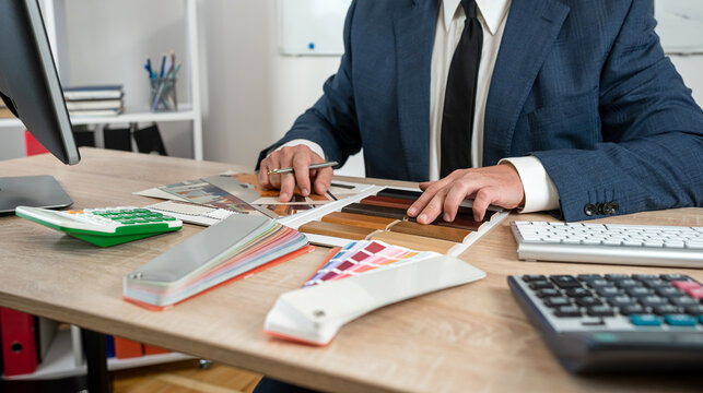 Architect working with blueprints and color sample computer at office, creatice workplace