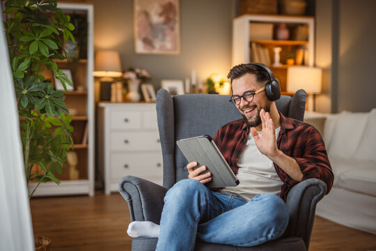 man with headphones sit in the armchair use tablet for video call