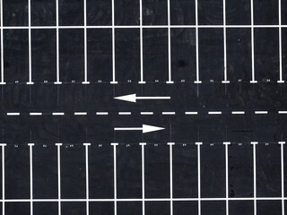 Aerial view of an empty parking lot with white lane markings and directional arrows. Ideal for urban planning, transportation, and parking management industries. © Dragoș Asaftei