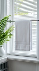 Fototapeta premium A simple yet stylish bathroom displays a pristine white towel hanging on a chrome bar. The space includes a sleek sink and a touch of greenery, creating a fresh atmosphere