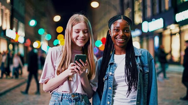Women on city street smiling at devices