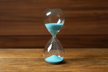 Modern hourglass on wooden background. Hourglass time concept for business deadline, urgency and...