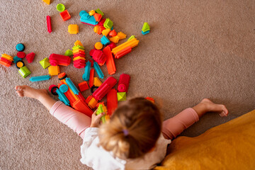 Little girl enjoying creative playtime with colorful bristle blocks, enhancing fine motor skills...
