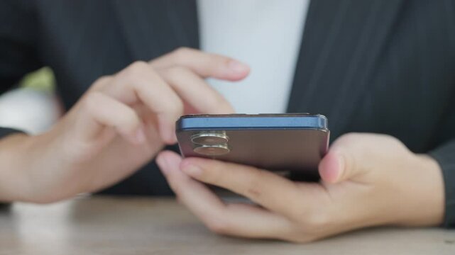 A woman is holding a cell phone and texting. She is wearing a suit and tie. Concept of professionalism and formality