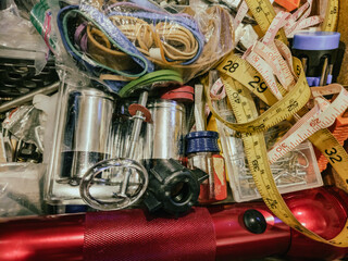 close-up of household junk drawer. random items measuring tape rubber bands nuts bolts nails brads...