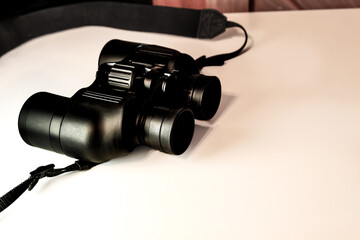 close-up of black binoculars retro vintage activities hobbies bird watching travel adventure vacation space for copy slideshow template isolated on a white backdrop table with space for copy