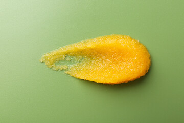 Smear of body scrub on green background, top view