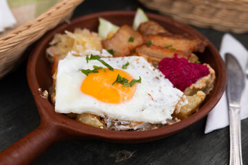 Scrambled eggs with fried bacon and potatoes served on plate