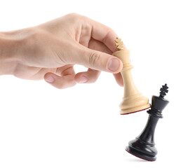 Man with white chess king knocking over black one on white background, closeup. Competition concept