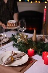 Woman setting table for Christmas dinner at home, selective focus
