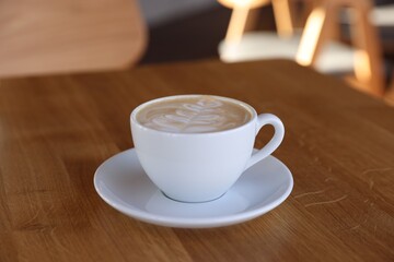 Cup of aromatic coffee on wooden table in cafe, closeup