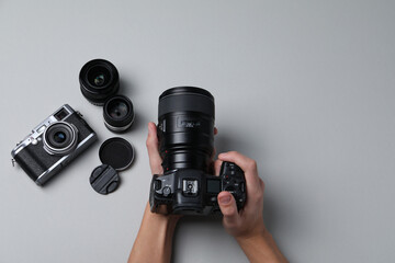 Photographer with professional camera on grey background, top view