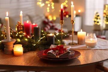 Festive table setting in room decorated for Christmas, closeup. Bokeh effect