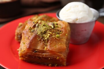 Tasty baklava with chopped nuts and scoop of ice cream on table, closeup