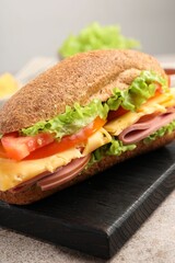 Delicious baguette sandwich with ham on grey table, closeup