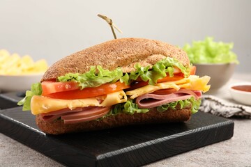 Delicious baguette sandwich with ham on grey table, closeup