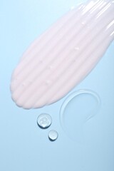 Cream and gel samples on light blue background, top view