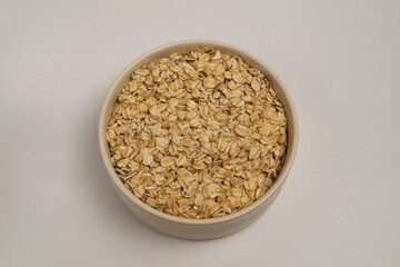 A bowl of oatmeal in a light-colored ceramic dish on a white background, offering a nutritious and energy-packed vegetarian breakfast to kickstart your day with essential vitamins and minerals