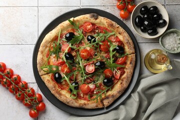 Tasty pizza with black olives, tomatoes and arugula served on light tiled table, flat lay