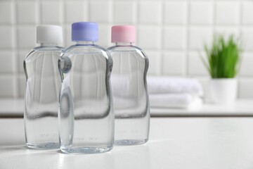 Baby oil in bottles on white table against blurred background. Space for text