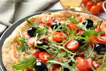 Tasty pizza with tomatoes, olives and arugula on table, closeup