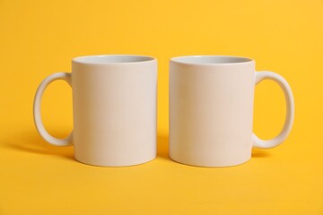 Two blank mugs for branding on orange background. Mockup for design