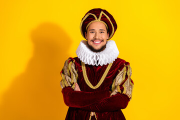 Cheerful man in royal costume with yellow background emphasizing historic elegance