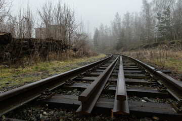 Obraz premium Abandoned rail tracks in an industrail zone covered in cold winter fog