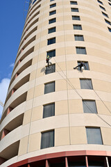 Climber clean windows on the side of an office building over blue sky background
