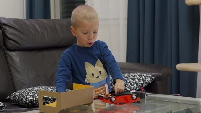 Impatient child unboxing new toy at home. Excited little boy unpacks remote-controlled transformer car.
