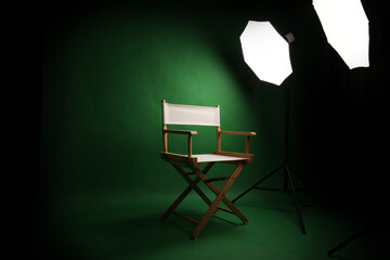 Photo studio with green screen background and wooden stool against professional lighting equipment....