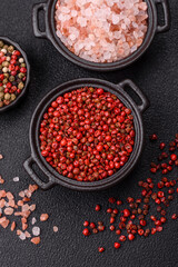 Spice, allspice peas in red or pink color in a bowl on a black concrete background