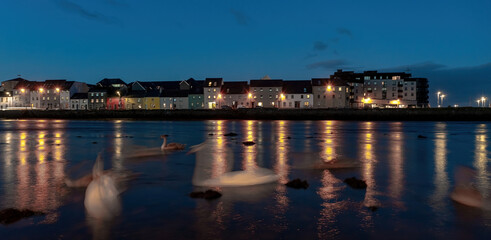Obraz premium A night shot of swans in motion blur, with The Long Walk in the background. Galway, Ireland